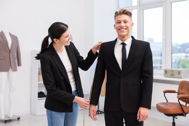 Photo of Tailor measuring jacket on man in atelier