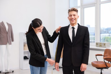 Photo of Tailor measuring jacket on man in atelier