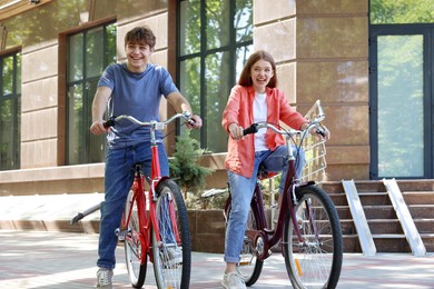 Photo of Teenage girl and boy riding bicycles on city street