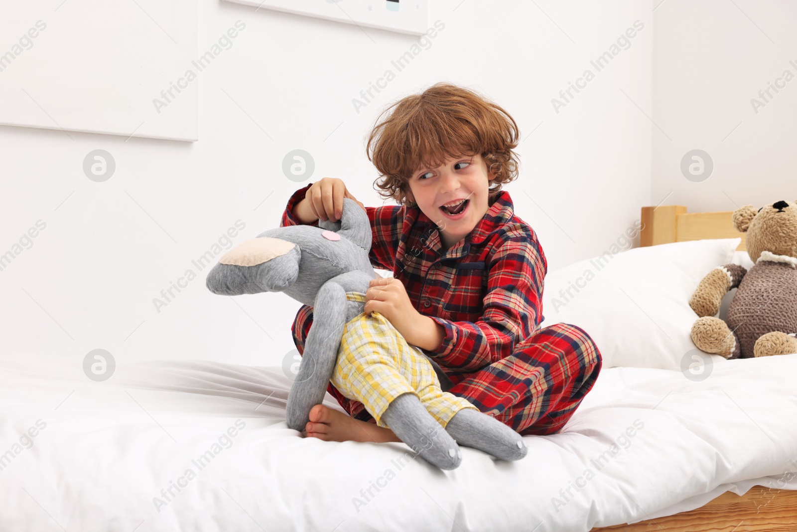 Photo of Little boy with toy elephant on bed at home
