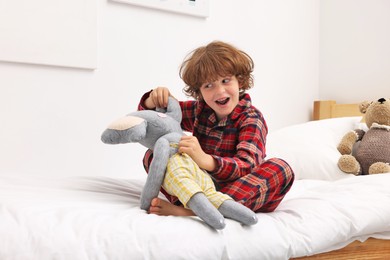Photo of Little boy with toy elephant on bed at home