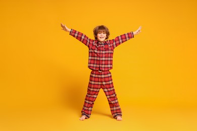 Photo of Cute little boy in pajamas on yellow background