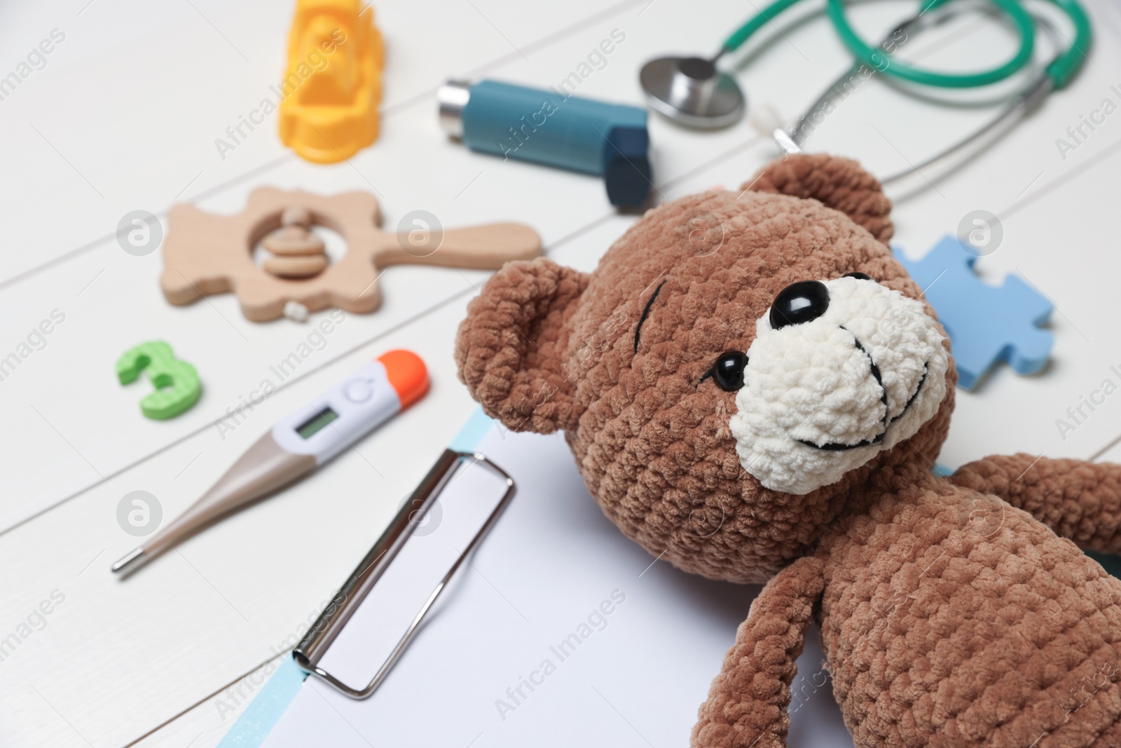 Photo of Pediatrics concept. Toy bear and thermometer on white wooden background, closeup