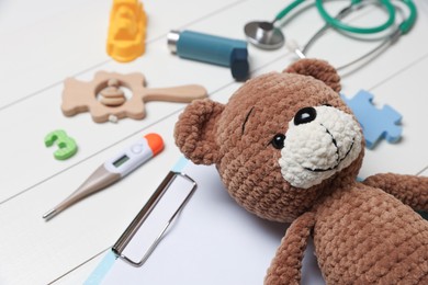 Photo of Pediatrics concept. Toy bear and thermometer on white wooden background, closeup
