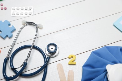 Photo of Pediatrics concept. Toys, stethoscope and pills on white wooden background, closeup. Space for text