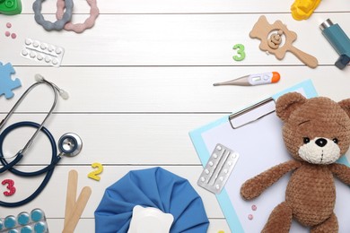 Photo of Pediatrics concept. Toy bear, clipboard and pills on white wooden background, flat lay. Space for text