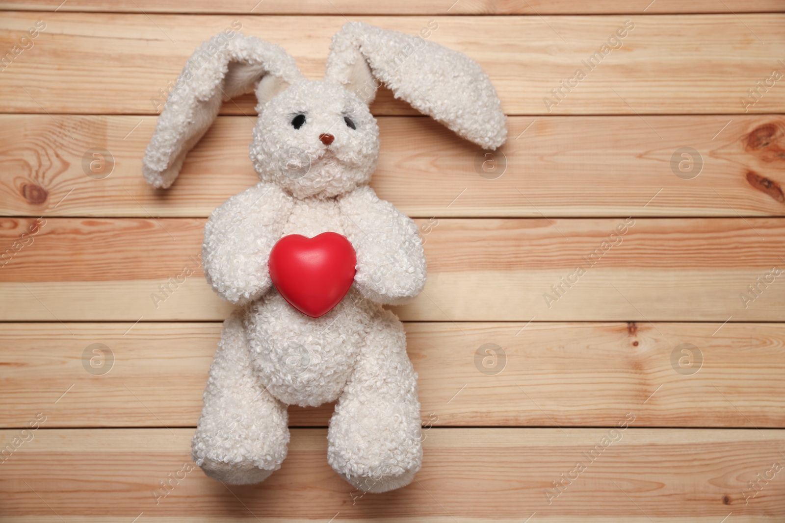 Photo of Pediatrics concept. Toy bunny and heart on wooden background, top view. Space for text