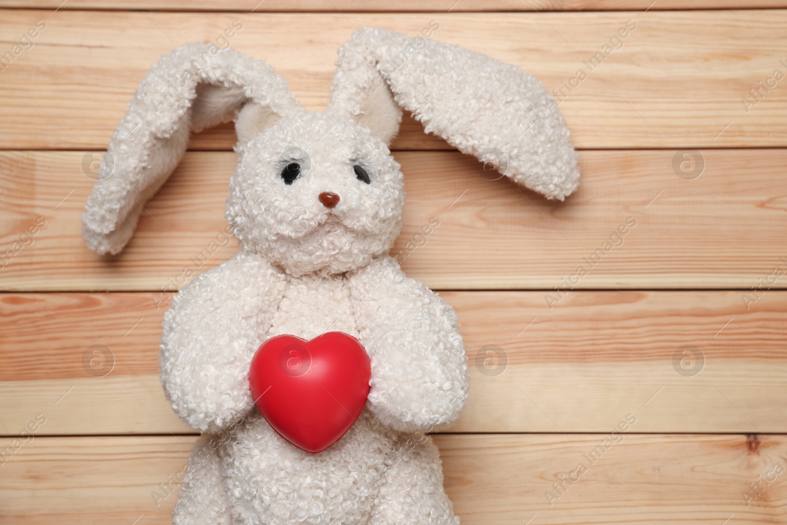 Photo of Pediatrics concept. Toy bunny and heart on wooden background, top view. Space for text