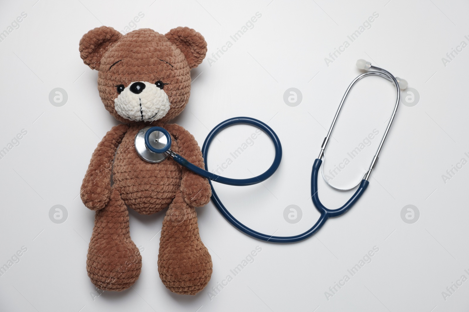 Photo of Pediatrics concept. Toy bear with stethoscope on white background, top view