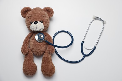 Photo of Pediatrics concept. Toy bear with stethoscope on white background, top view