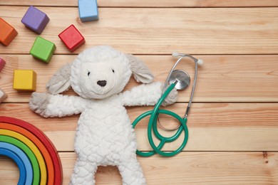 Photo of Pediatrics concept. Toys and stethoscope on wooden background, flat lay. Space for text
