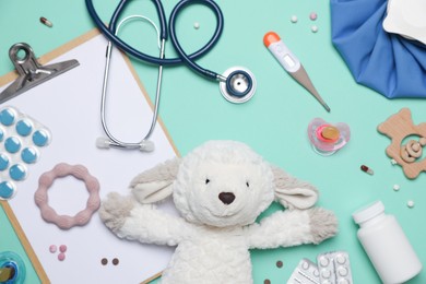 Photo of Pediatrics concept. Toy sheep with stethoscope, thermometer, clipboard and pills on turquoise background, flat lay