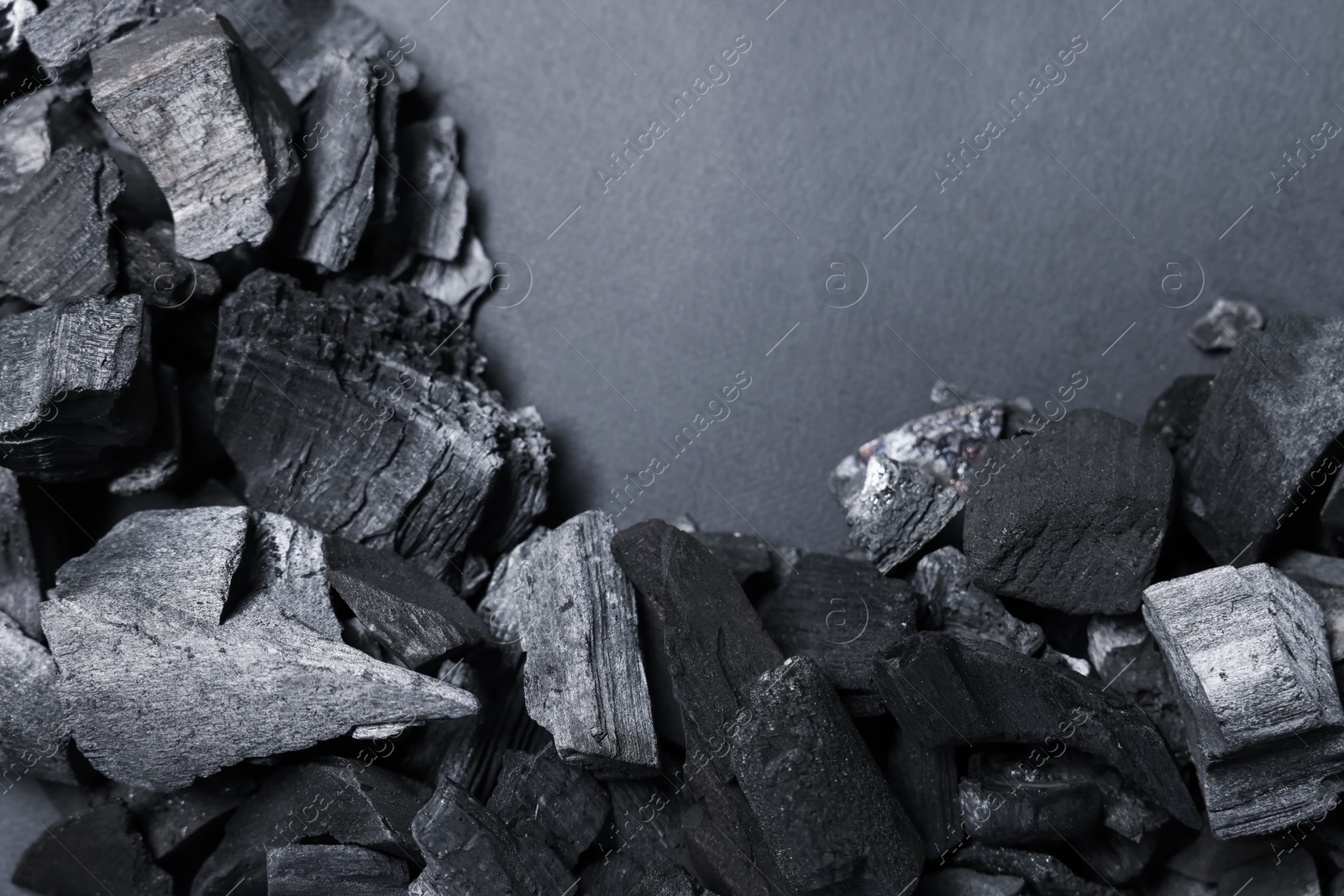 Photo of Pieces of black coals on grey background, top view. Space for text