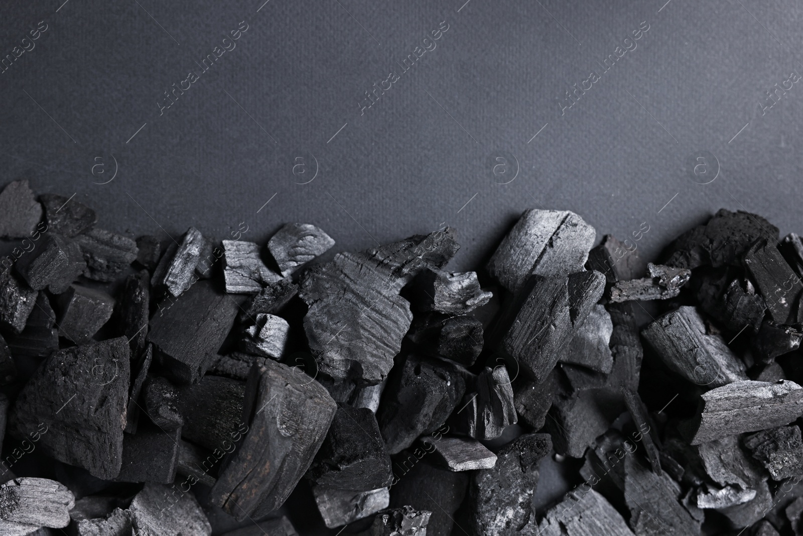 Photo of Pieces of black coals on grey background, top view. Space for text