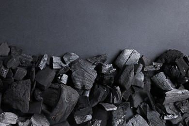 Photo of Pieces of black coals on grey background, top view. Space for text