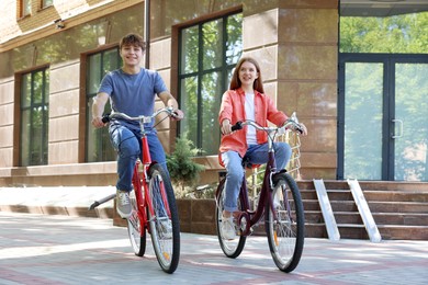 Photo of Teenage girl and boy riding bicycles on city street