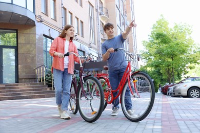 Photo of Teenage girl and boy with bicycles on city street