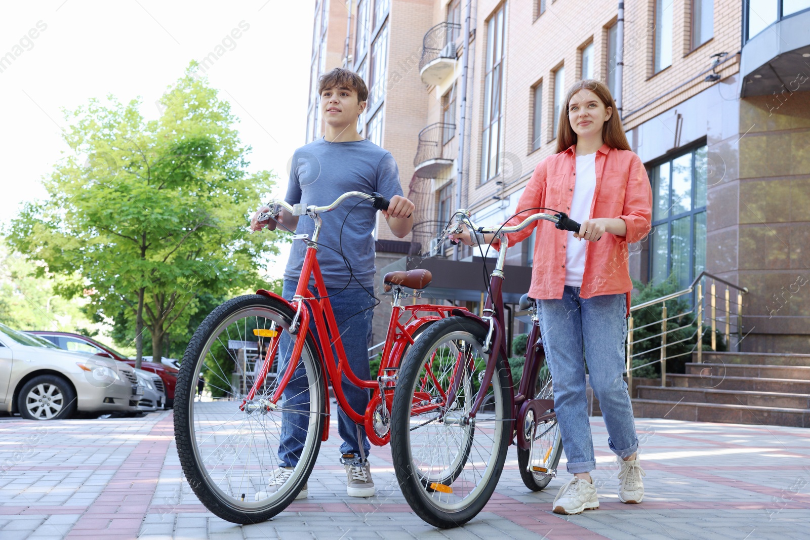 Photo of Teenage girl and boy with bicycles on city street