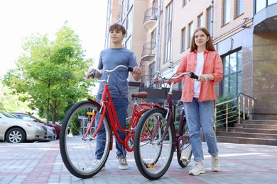 Photo of Teenage girl and boy with bicycles on city street