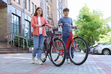 Photo of Teenage girl and boy with bicycles on city street