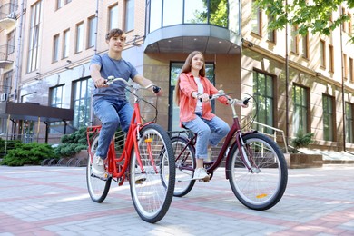 Photo of Teenage girl and boy riding bicycles on city street