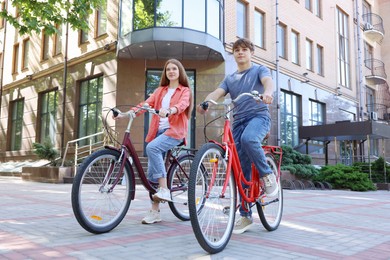Photo of Teenage girl and boy riding bicycles on city street