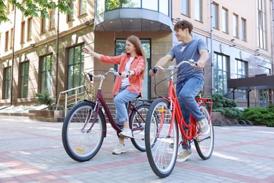 Photo of Teenage girl and boy riding bicycles on city street