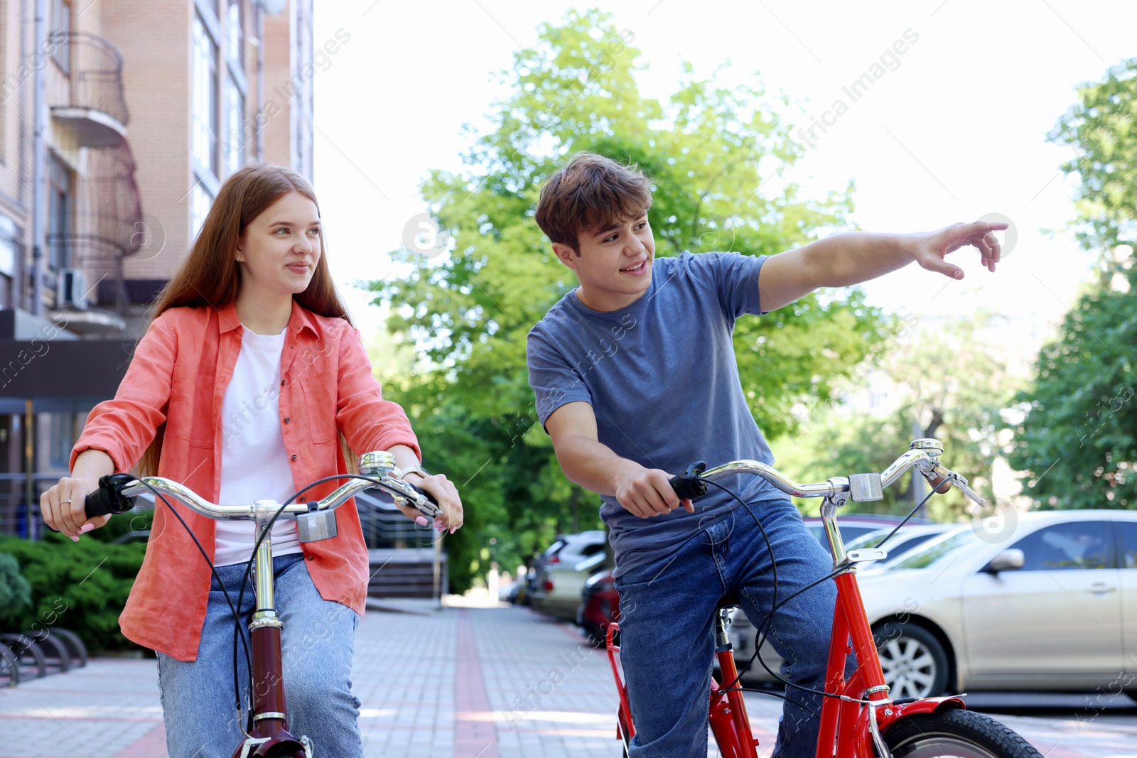 Photo of Teenage girl and boy riding bicycles on city street