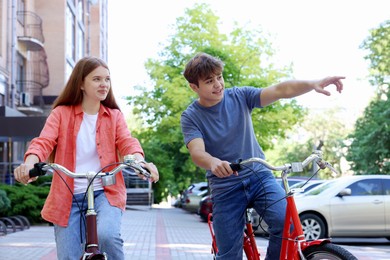 Photo of Teenage girl and boy riding bicycles on city street