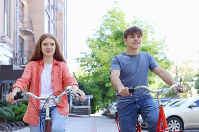 Photo of Teenage girl and boy riding bicycles on city street