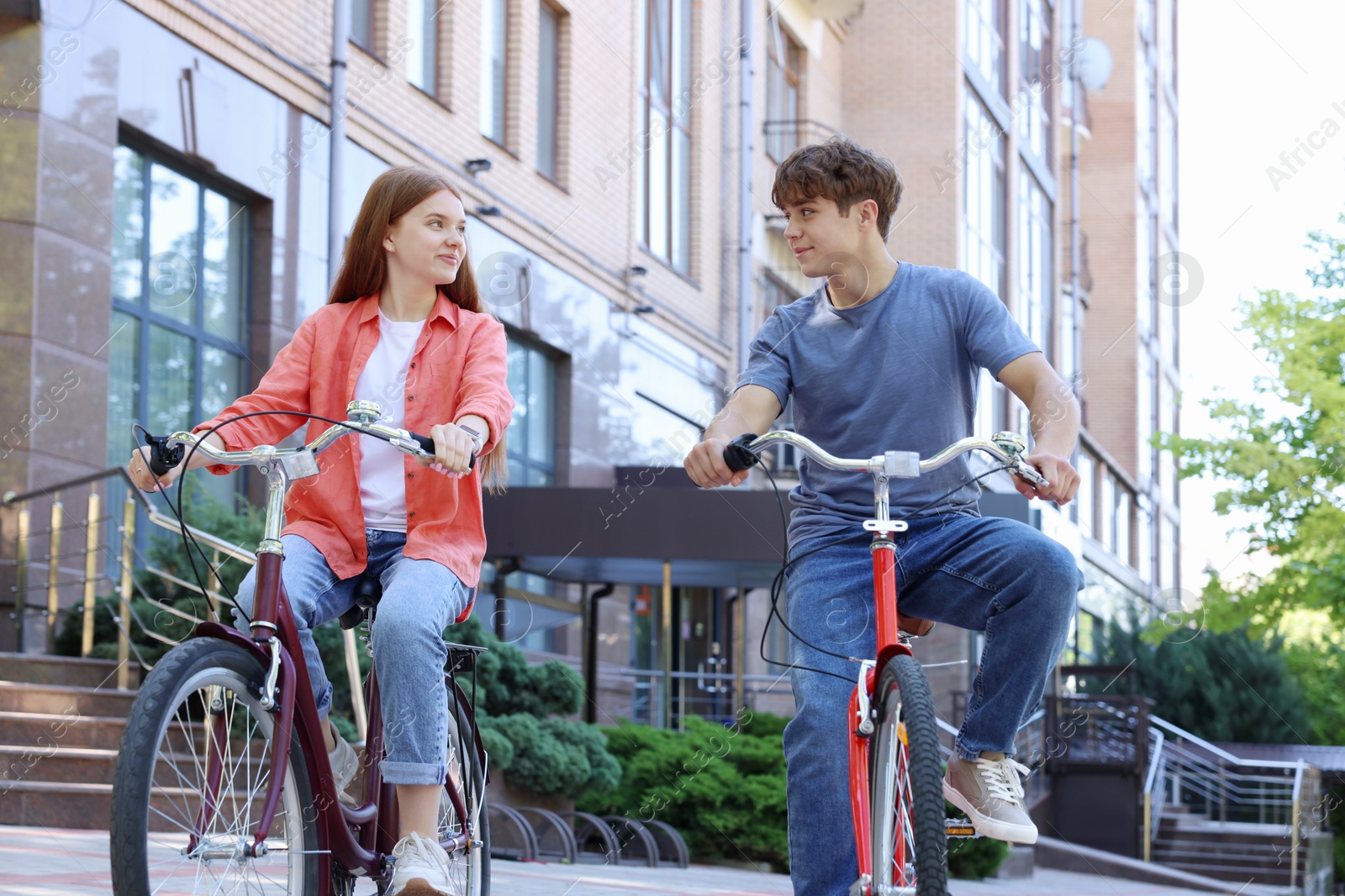 Photo of Teenage girl and boy riding bicycles on city street