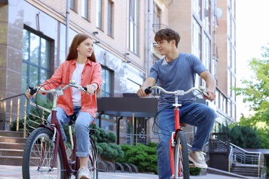 Photo of Teenage girl and boy riding bicycles on city street