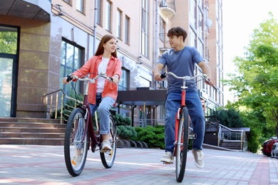 Photo of Teenage girl and boy riding bicycles on city street