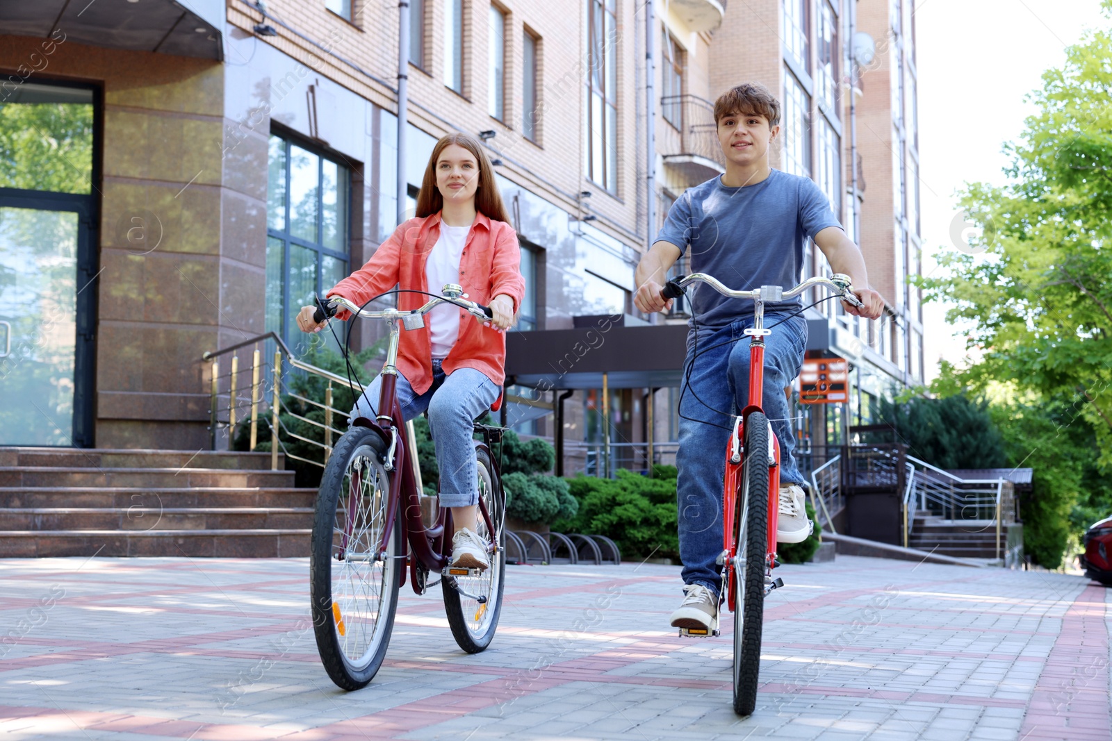 Photo of Teenage girl and boy riding bicycles on city street