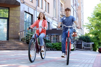 Photo of Teenage girl and boy riding bicycles on city street