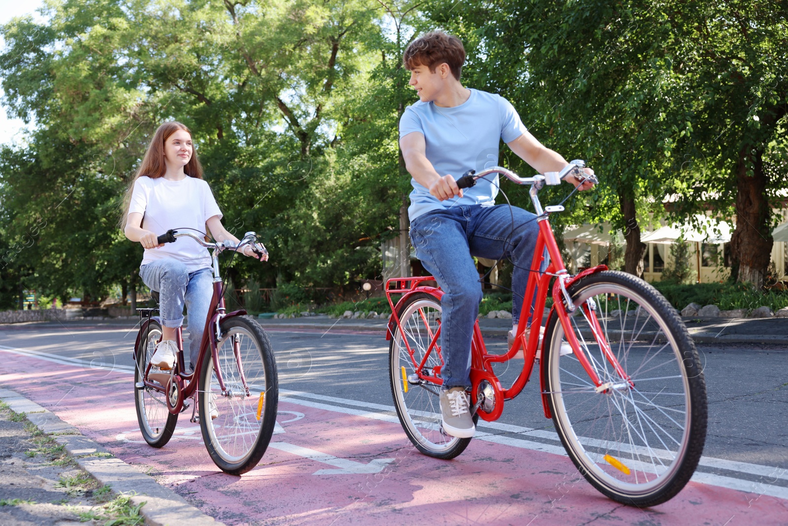 Photo of Teenage girl and boy riding bicycles on city street