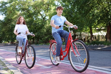 Photo of Teenage girl and boy riding bicycles on city street