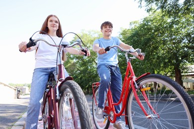 Photo of Teenage girl and boy riding bicycles on city street, low angle view