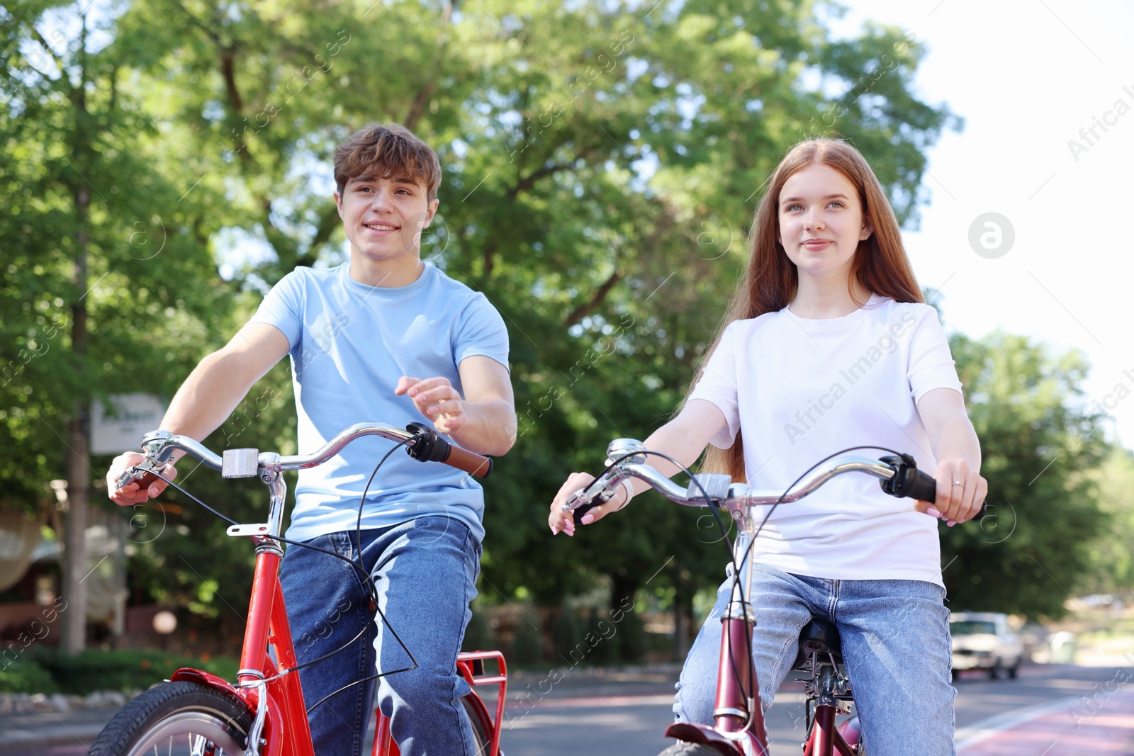 Photo of Teenage girl and boy riding bicycles on city street