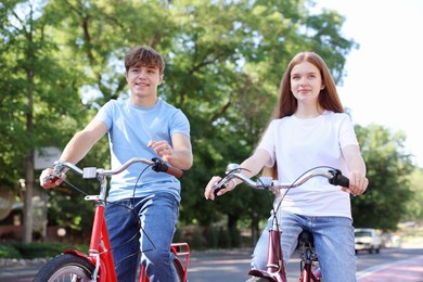 Photo of Teenage girl and boy riding bicycles on city street