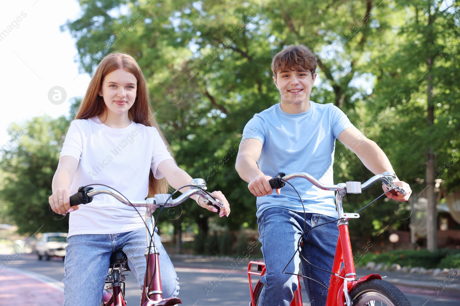 Photo of Teenage girl and boy riding bicycles on city street