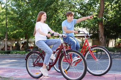 Photo of Teenage girl and boy riding bicycles on city street