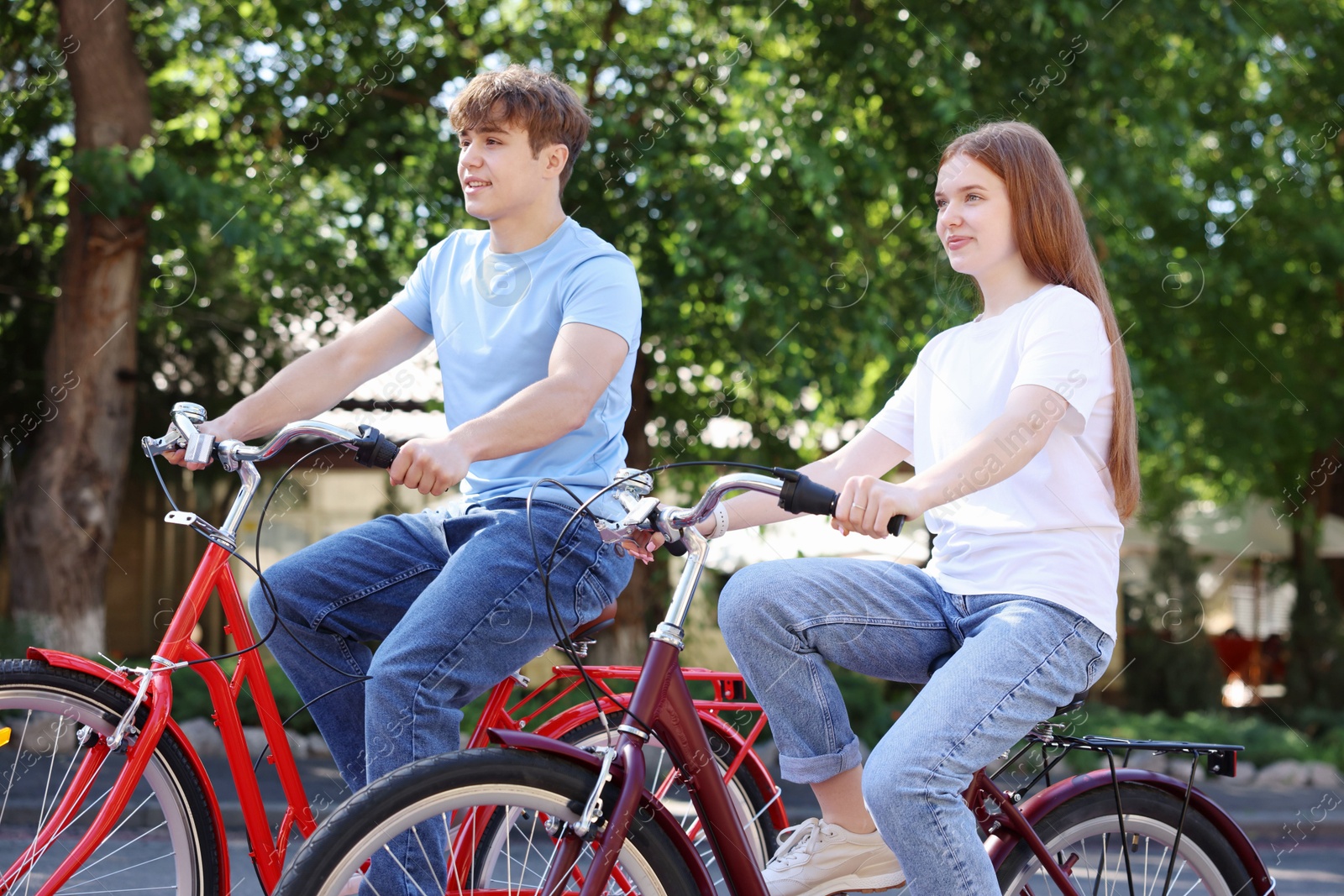 Photo of Teenage girl and boy riding bicycles on city street