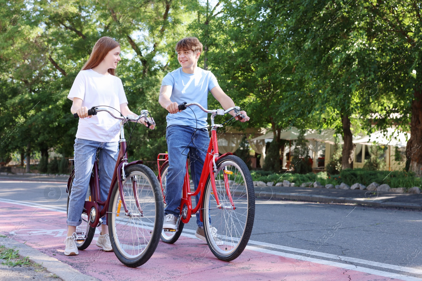 Photo of Teenage girl and boy riding bicycles on city street