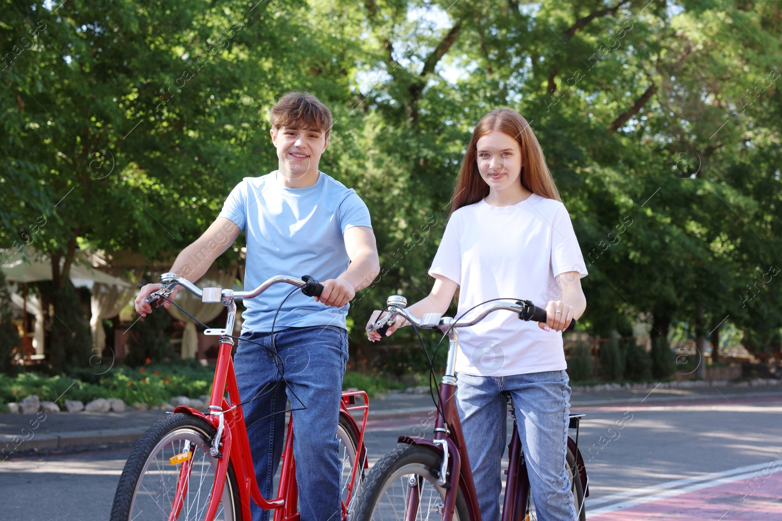 Photo of Teenage girl and boy riding bicycles on city street