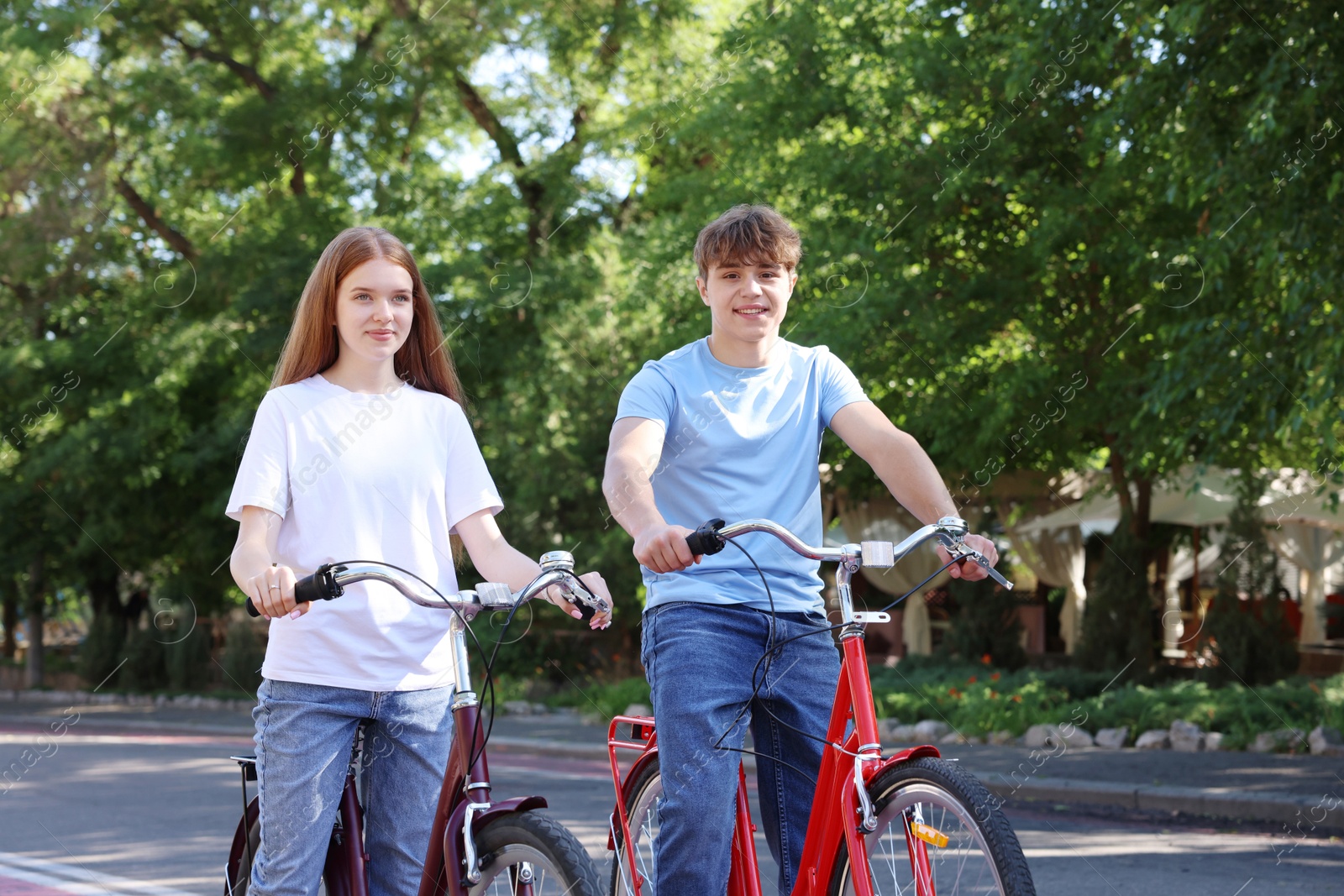 Photo of Teenage girl and boy riding bicycles on city street