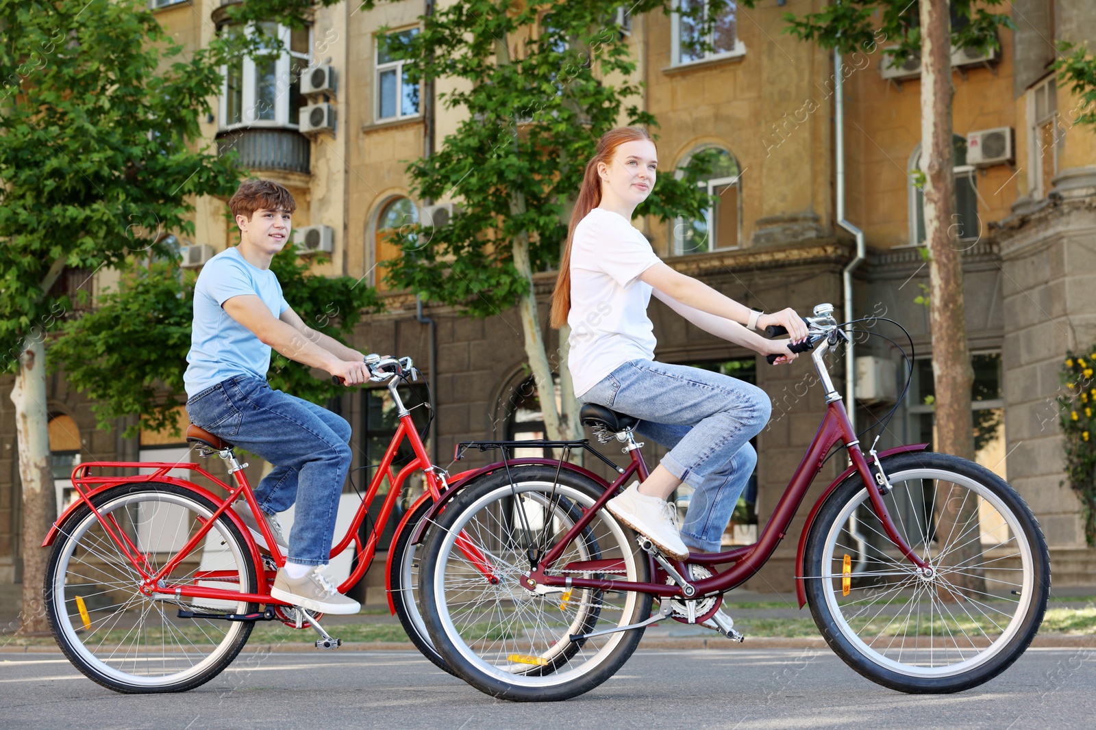 Photo of Teenage girl and boy riding bicycles on city street