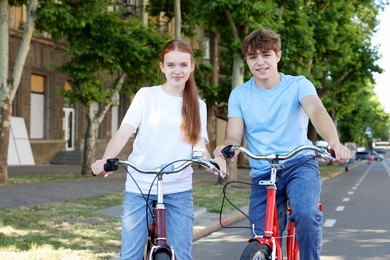 Photo of Teenage girl and boy riding bicycles on city street