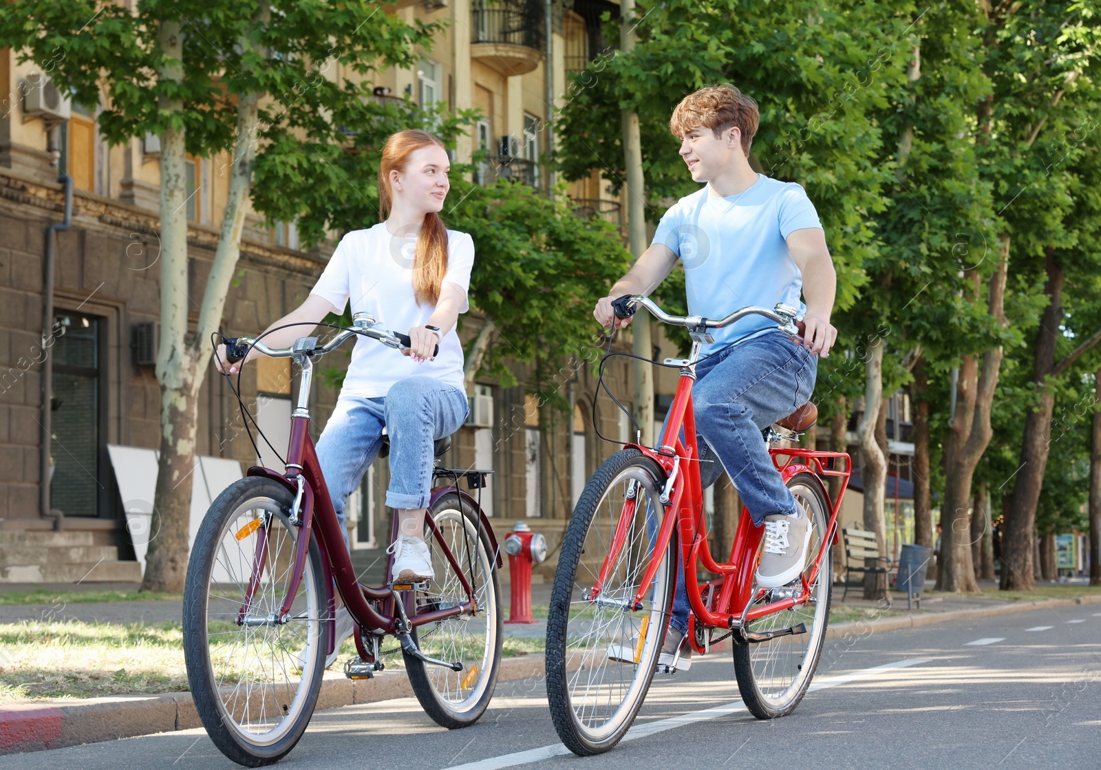 Photo of Teenage girl and boy riding bicycles on city street