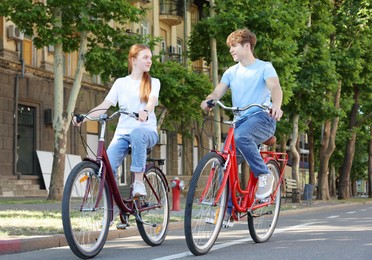 Photo of Teenage girl and boy riding bicycles on city street